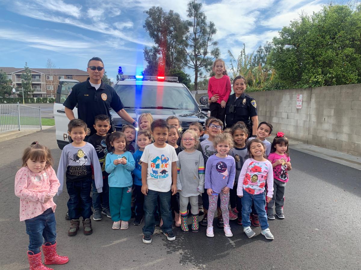 officers with kids in front of cars