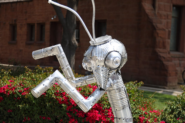 A portrait of an art piece made from recycled cans created by Mariposa Alley artist, Martin Sanchez which is inspired by Riverside Insect Fair Praying Mantis logo.