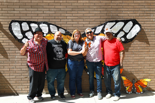 volunteers and city employees posing in front of butterfly