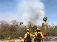 Firefighters in the foreground while smoke from riverbottom fire is in background